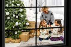年轻的大家庭庆祝圣诞节享受晚餐视图窗口装饰生活房间树蜡烛灯快乐父母吃孩子们