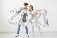 假期节日聚会，派对概念快乐爱的夫妇持有银气球白色背景一年庆祝活动