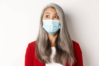科维德流感大流行业务概念关闭优雅的亚洲高级夫人盯着上左角落里穿医疗面具冠状病毒白色背景