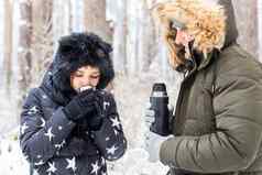 年轻的夫妇爱喝热喝热水瓶享受冬天自然