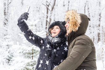 季节爱技术休闲概念快乐夫妇采取自拍智能手机冬天背景