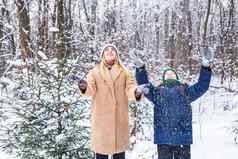 育儿有趣的季节概念快乐妈妈。儿子有趣的玩雪冬天森林