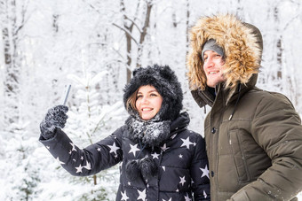 季节爱技术休闲概念快乐夫妇采取自拍智能手机冬天背景