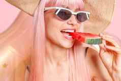 肖像女人粉红色的头发泳衣太阳镜西瓜片充气环游泳摆姿势孤立的粉红色的背景