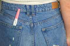 年轻的女人积极的怀孕测试口袋里牛仔裤特写镜头
