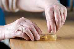 特写镜头上了年纪的高级女人的手采取药物治疗周药丸盒子木表格业务健康概念
