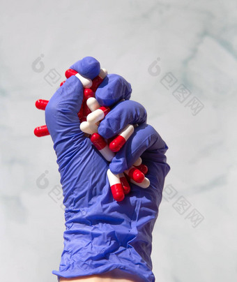 手蓝色的乳胶手套抓住手完整的药物胶囊维生素药物药物治疗健康业务概念