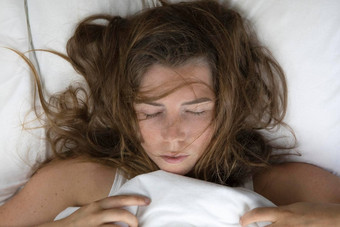 美丽的年轻的女人睡觉床上混乱的棕色（的）头发前视图说谎白色床上表雀斑