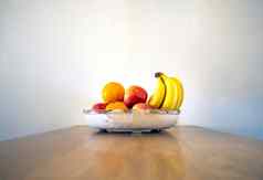 健康的新鲜的水果碗木表格香蕉橙子苹果白色墙现代设计木表格复制空间健康的生活前面视图