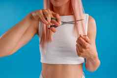 裁剪拍摄女人粉红色的头发切割头发剪刀站孤立的蓝色的工作室背景