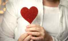 女手持有闪闪发光的红色的心身体采取护理健康情人节一天概念浪漫的设计