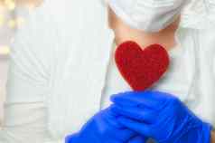 医疗保健工人持有红色的心蓝色的医疗手套疫情冠状病毒病毒健康爱情人节概念