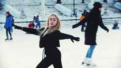 年轻的金发女郎有吸引力的女人专业数字溜冰者滑冰在户外冰溜冰场人