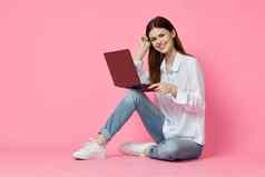 快乐的女人移动PC坐着地板上粉红色的背景互联网技术