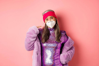 科维德流感大流行时尚概念亚洲高级女人时尚的闪闪发光的衣服抱怨脸面具指出呼吸器皱着眉头粉红色的背景