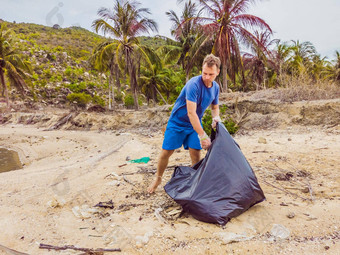 男人。手套选择塑料袋污染海问题泄漏<strong>垃圾垃圾垃圾</strong>海滩沙子引起的人为造成的污染<strong>环境</strong>运动清洁志愿者概念