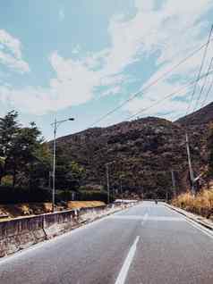 干沥青空汽车路混凝土障碍标记行阳光明媚的夏天一天蓝色的多云的天空车旅行旅行概念背景故事垂直格式黑暗绿色风格