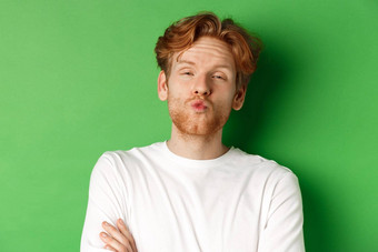 情绪时尚概念愚蠢的红色头发的人的家伙胡子皱纹嘴唇倾斜吻站绿色背景