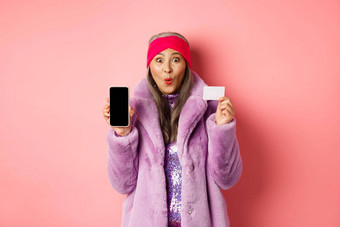 特殊的促销活动兴奋亚洲高级女人显示空白智能手机屏幕塑料信贷卡检查在线提供粉红色的背景