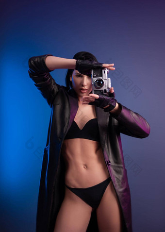 浅黑肤色的女人摄影师女孩内衣皮革雨衣提出了照片工作室相机