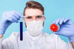 科维德疫苗发展医学概念男人。科学家流感面具保护手套持有模型冠状病毒测试管