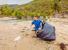 男人。手套选择塑料袋污染海问题泄漏垃圾垃圾垃圾海滩沙子引起的人为造成的污染环境运动清洁志愿者概念