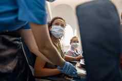 女人保护脸面具女儿女飞行之前帮助调整紧安全带飞机安全旅行