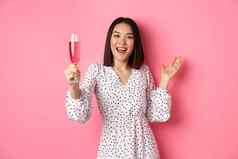 快乐亚洲女人庆祝烤面包聚会，派对提高玻璃香槟微笑站衣服粉红色的背景
