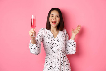 快乐亚洲女人庆祝烤面包聚会，<strong>派</strong>对提高玻璃香槟<strong>微</strong>笑站衣服粉红色的背景