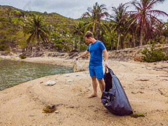 男人。手套选择塑料袋污染海问题泄漏<strong>垃圾垃圾垃圾</strong>海滩沙子引起的人为造成的污染<strong>环境</strong>运动清洁志愿者概念