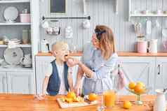 健康的食物新鲜的水果多汁的橙子妈妈。儿子微笑早餐厨房明亮的早....厨房