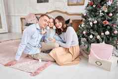 爱的家庭妈妈爸爸拥抱女儿父母婴儿孩子有趣的圣诞节树白色壁炉在室内快乐圣诞节快乐一年快乐的漂亮的人