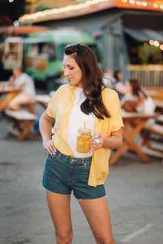 女孩黄色的衬衫短裤玻璃柠檬汁站街