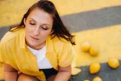 女孩柠檬黄色的衬衫短裤黑色的鞋子坐在黄色的行人穿越城市柠檬情绪
