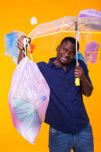 问题垃圾塑料回收<strong>污染环境</strong>概念有趣的非洲美国男人。携带垃圾回收黄色的背景