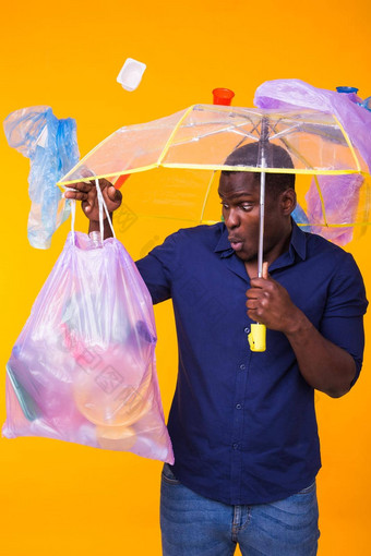问题垃圾塑料回收污染环境概念惊讶非洲美国男人。携带垃圾回收黄色的