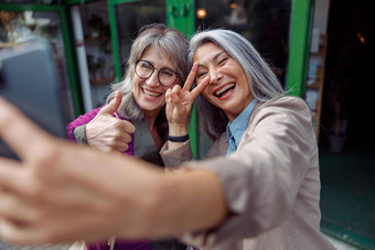 有吸引力的成熟的亚洲女人朋友自拍手势电话城市街