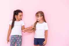 惊讶孩子们女孩显示白色t恤孤立的粉红色的背景童年生活方式概念模拟复制空间指出指数手指
