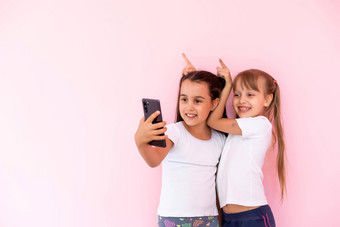 女孩玩智能手机粉红色的背景