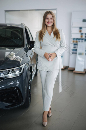 肖像华丽的女人展厅美丽的销售人员站车金发碧眼的头发女购买车