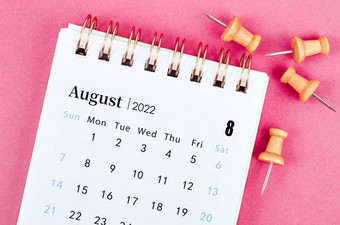 8月桌子上日历木销粉红色的背景