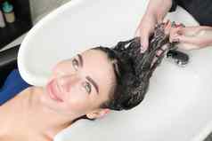 发型师的手洗长头发浅黑肤色的女人女人洗发水特殊的水槽洗头