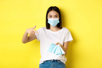 冠状病毒检疫医学概念年轻的亚洲女人指出手指医疗面具在户外站黄色的背景