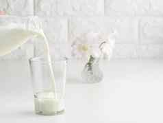 过程倒新鲜的牛奶塑料瓶玻璃杯白色表格