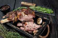 烤羊肉羊肉腿切片木托盘肉切肉刀黑色的木背景前视图