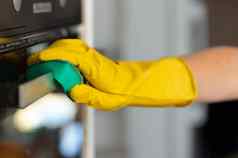 女人的手黄色的手套清洁通过烤箱