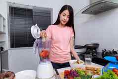 女人使蔬菜冰沙搅拌机厨房