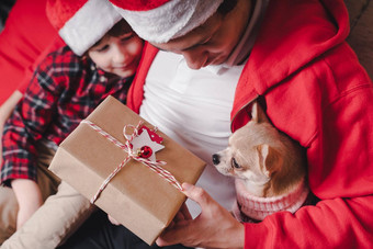快乐家庭圣诞老人他父亲孩子儿子给圣诞节礼物首页坐着沙发上生活房间小狗狗毛衣