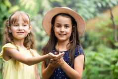 姐妹持有蝴蝶手孩子们探索自然家庭休闲孩子们夏天