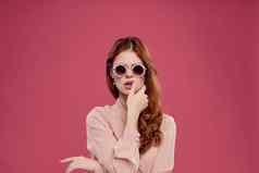 美丽的女人太阳镜现代风格魅力粉红色的背景